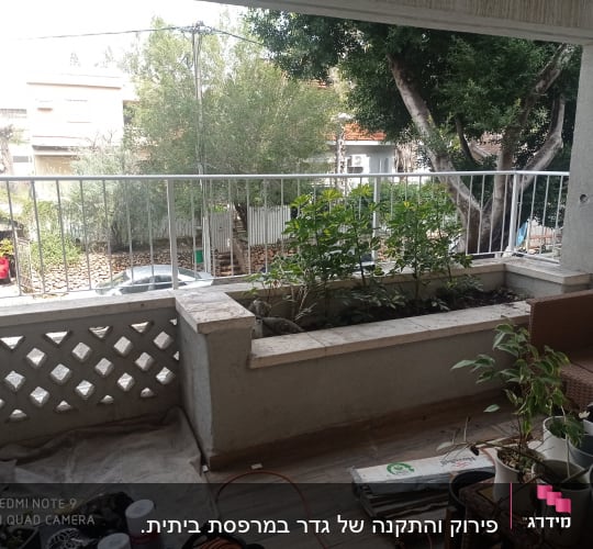 מעקה מתכת לבן במרפסת עם עציצים ירוקים